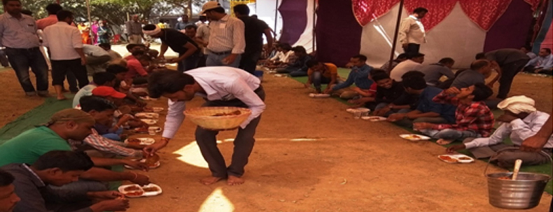 People participating in community lunch during rural social welfare program in India promoting unity and service