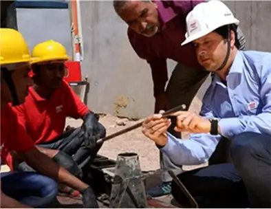 Engineer providing on-site training to construction workers on material quality testing
