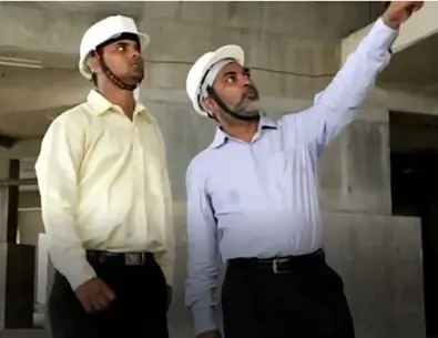 Two construction engineers wearing safety helmets inspecting a building site