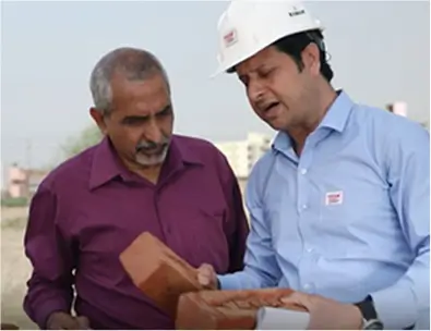 Engineer wearing safety helmet discussing brick quality and construction details with site supervisor