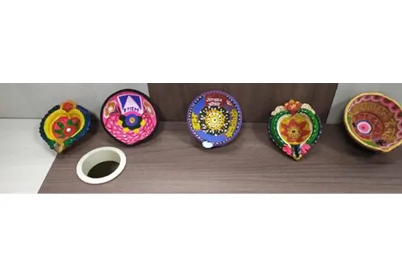 Colorful decorated Diwali diyas arranged on a table as part of a festive art display
