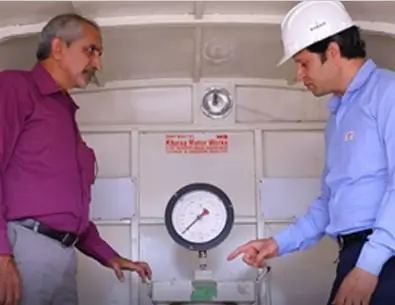 Two engineers inspecting a pressure gauge on industrial equipment