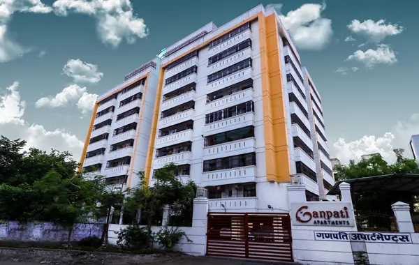 Multi-storey apartment building with white and orange exterior named Ganpati Apartments