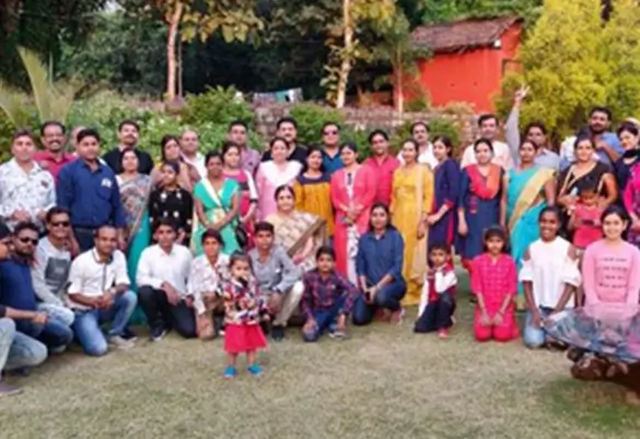 A large group of adults and children posing together outdoors in a garden setting during a gathering