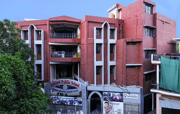 Red brick school building with entrance gate and signage visible