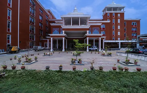 Front view of red-brick institutional building with pillars and potted plants outside
