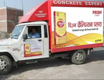 Prism Cement Concrete Expert vehicle at a construction site promoting Prism Champion Plus cement