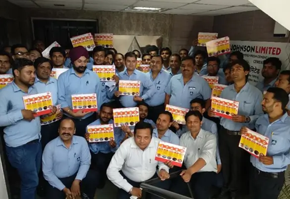 Prism Johnson employees holding awareness posters during an indoor training and development session group photo