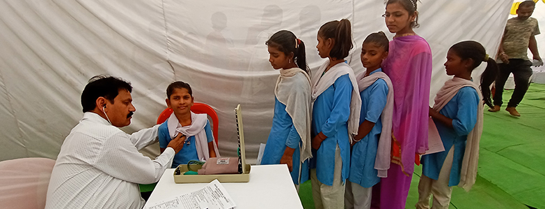 Doctor conducting health checkup for school girls during a medical camp organized by Prism Cement