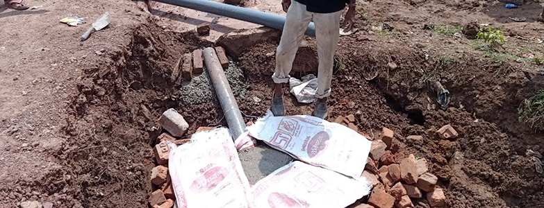 Worker installing underground water pipeline during rural village development