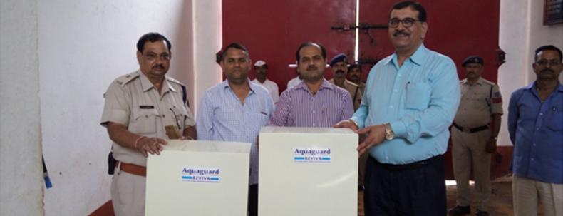 group of officials handing over two Aquaguard water purifiers during a donation event