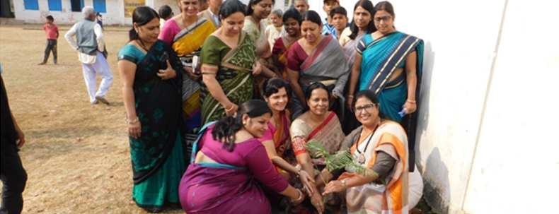 Group of women in sarees planting a tree together as part of an environment awareness event